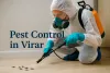 Pest control worker in Virar spraying pesticide on cockroaches indoors with protective gear and orange sprayer.