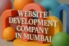 3D image with bold Lora font text “Website Development Company in Mumbai” over colorful abstract geometric shapes.
